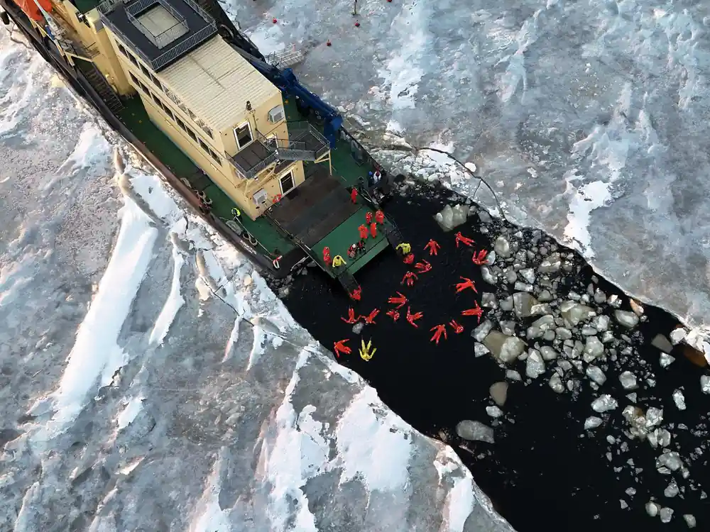Aerial view of passengers floating in a channel of broken ice beside the ship