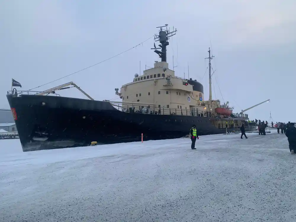 Arktis alongside the quay with people walking on the ice