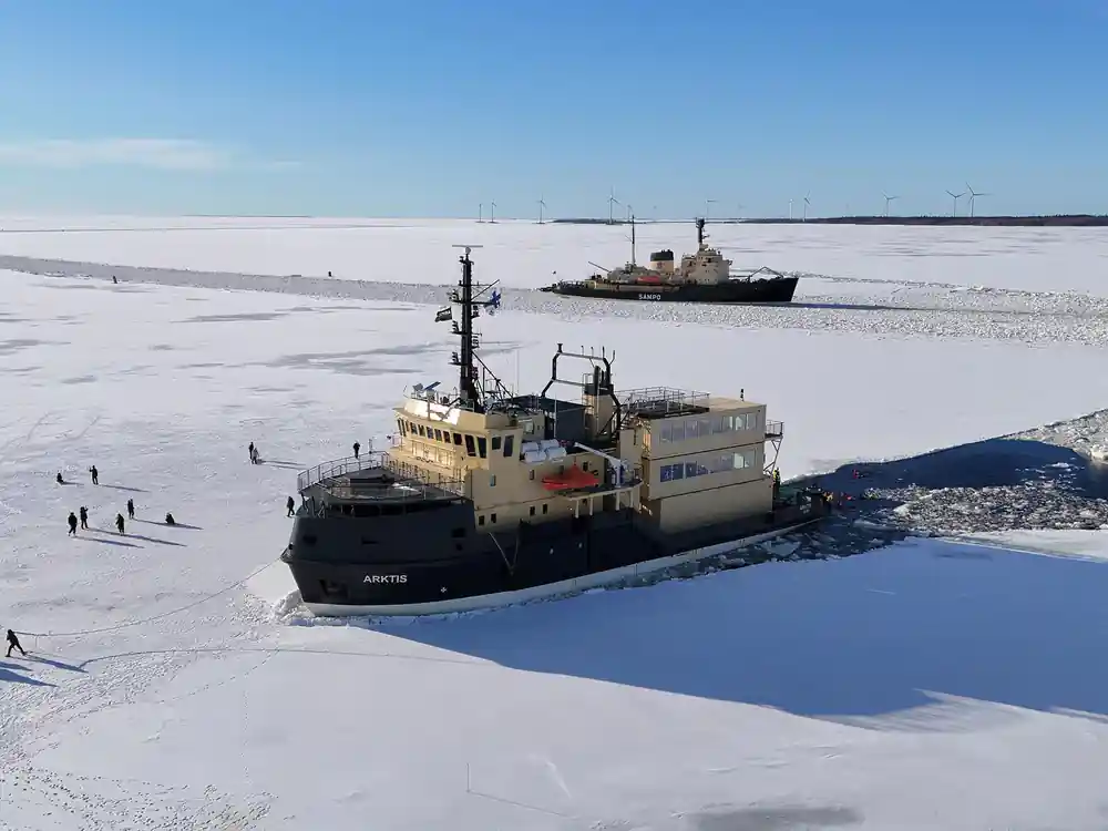 Arktis working through the ice seen from a distance across the field