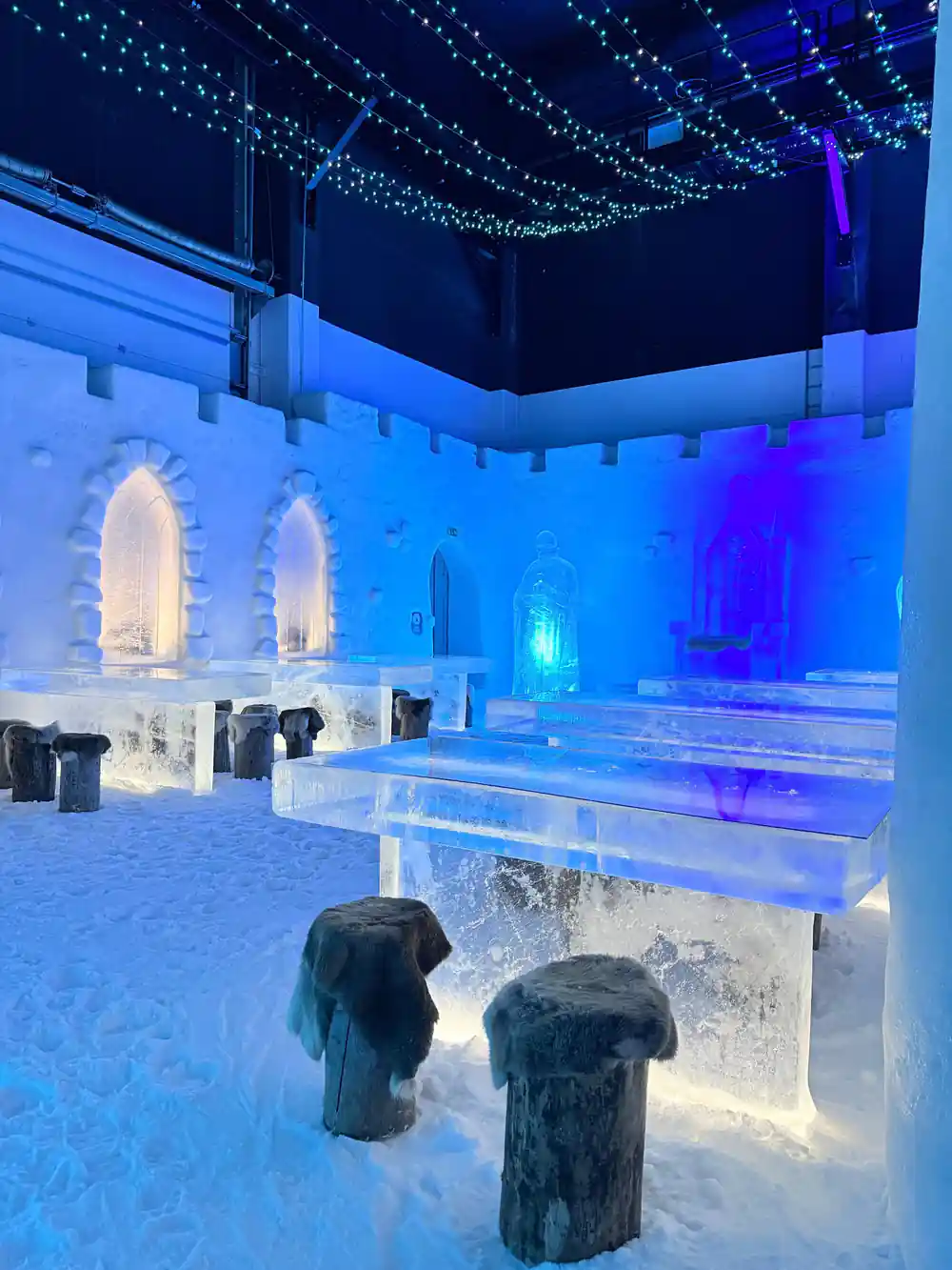 The blue-lit interior of the snow castle with ice tables and arches