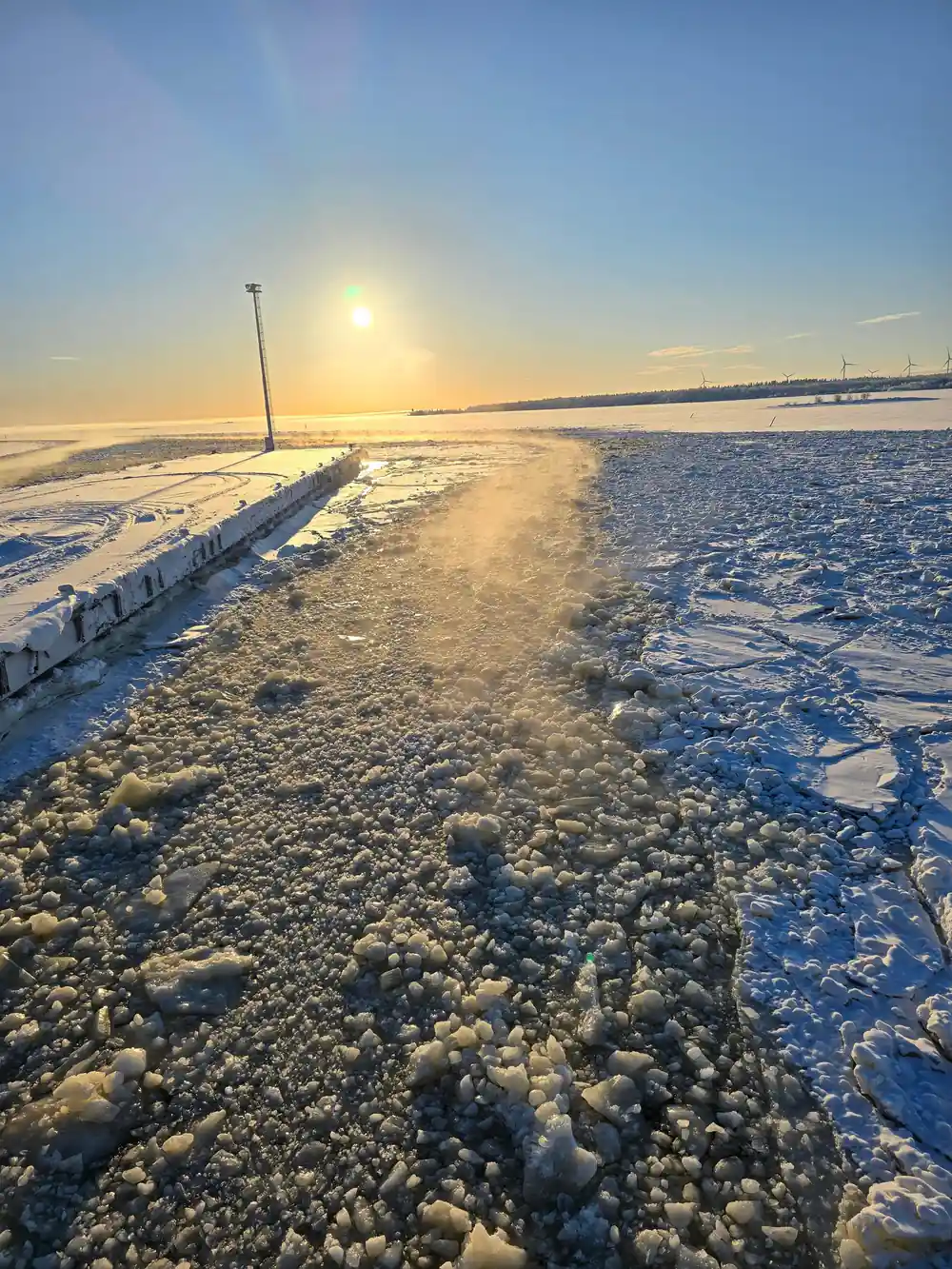 A channel of broken ice running to the horizon at sunset