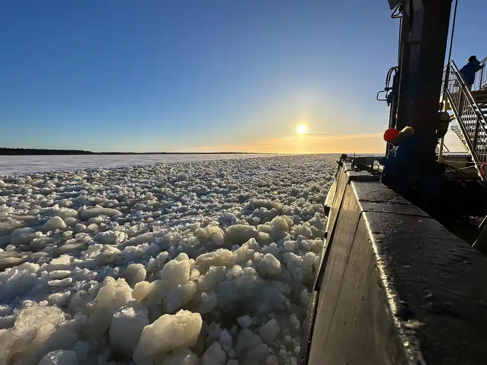 Pancake ice crowded against the hull under a low sun