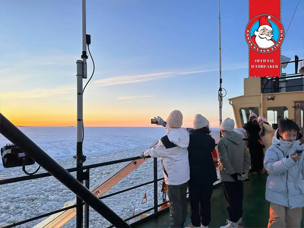 Passengers photographing from the ship rail at sunset over the ice