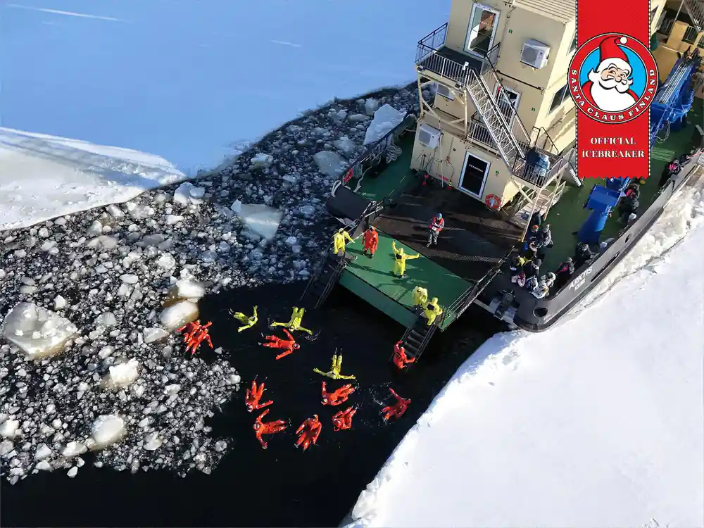 Passengers in survival suits on the ship stern deck beside broken ice