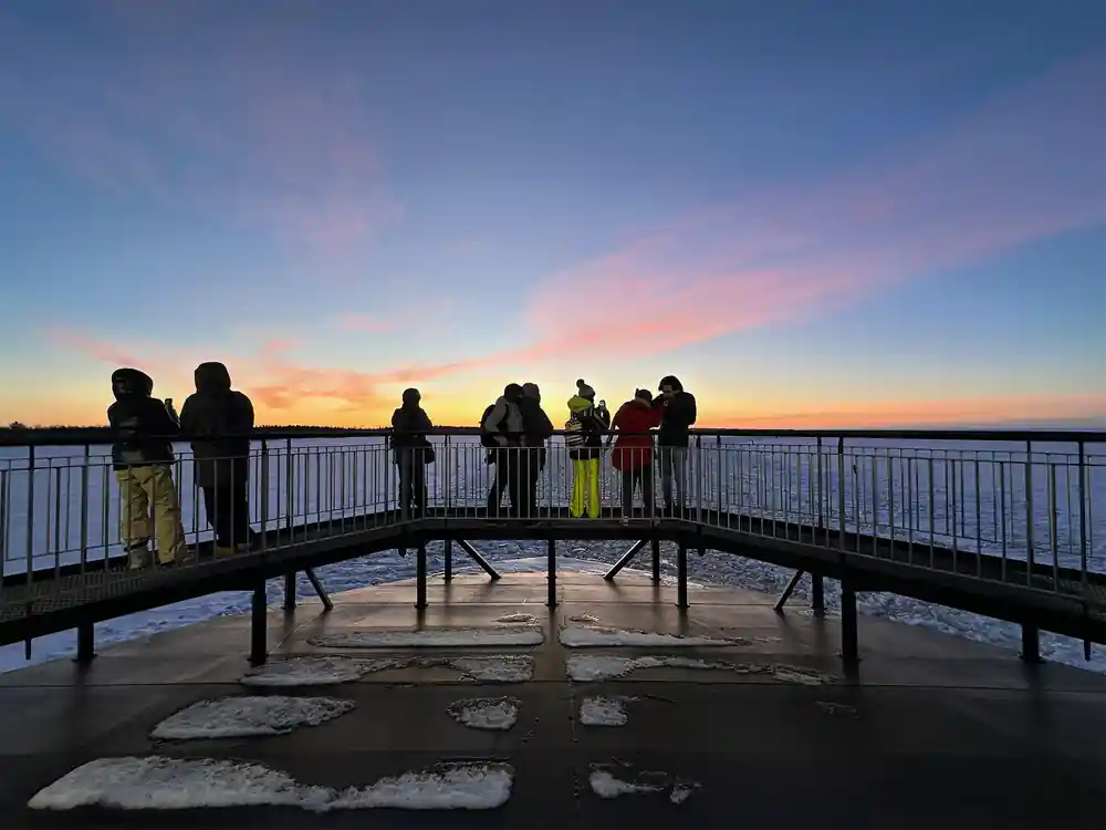 Passengers on a walkway over the ice at sunset