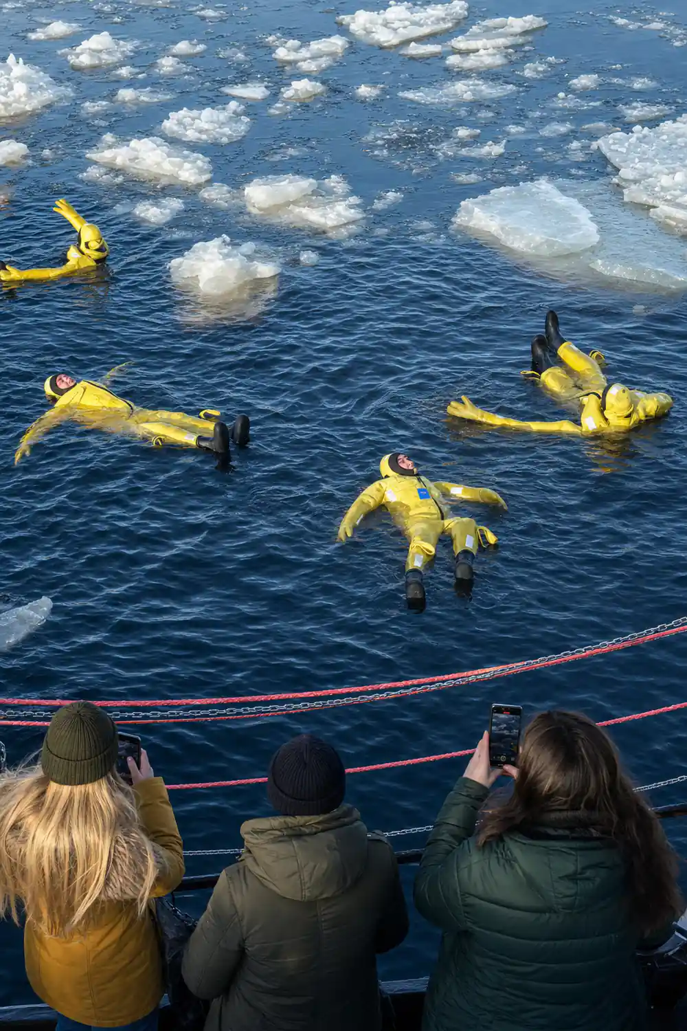 Passengers in yellow survival suits floating among broken ice plates