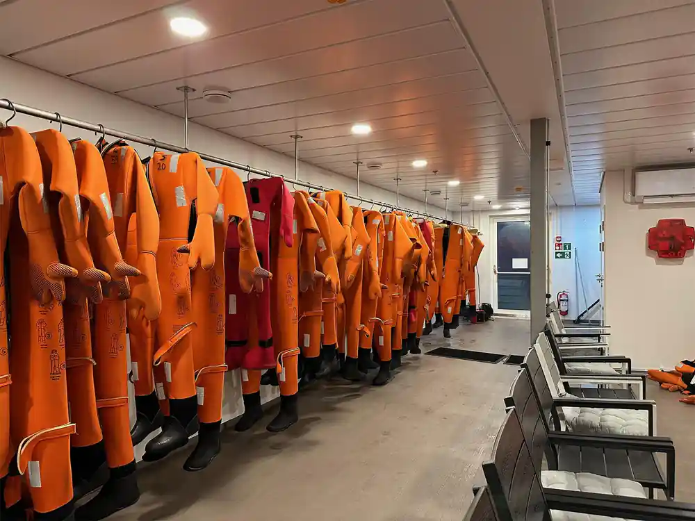 A rack of orange survival suits hanging in a changing room