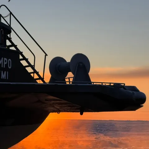 The icebreaker's bow at sunset with floaters in the water