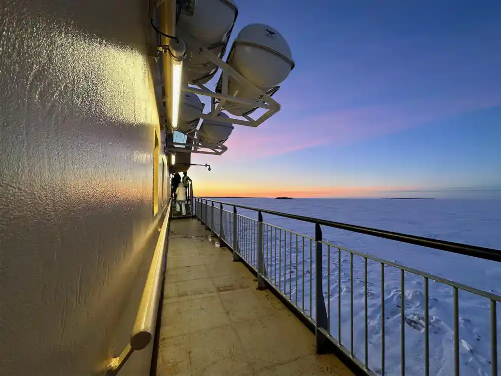 Ship lights along the rail at sunset over the frozen sea