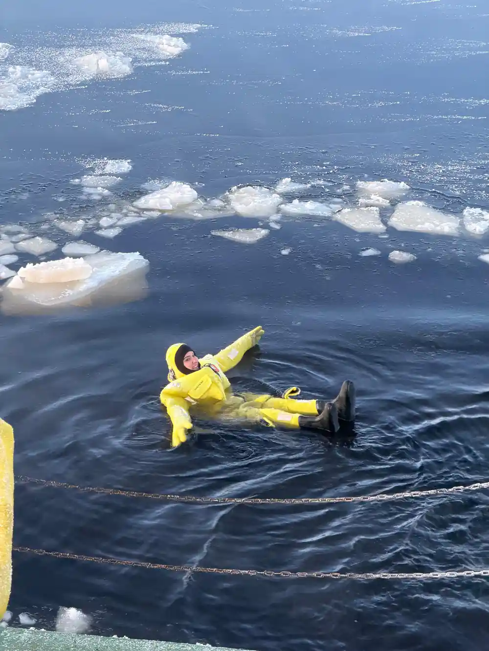 A single floater in a yellow suit in open water beside the ice