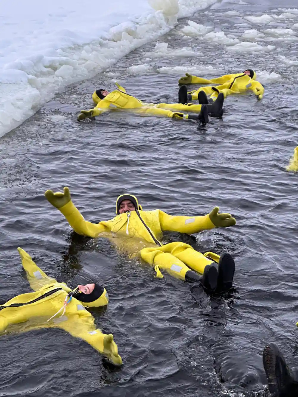 Two floaters in yellow suits lying back in the water