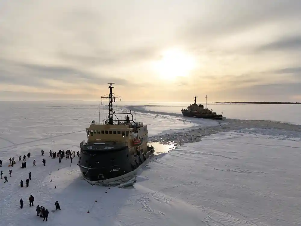 Two icebreakers in the ice with a low sun behind them