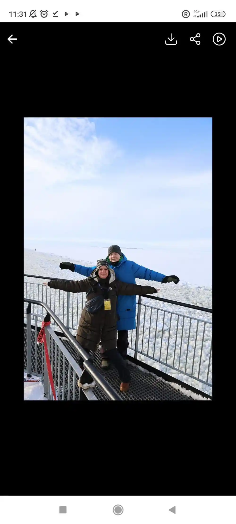 A visitor with arms spread on the ship deck above the ice
