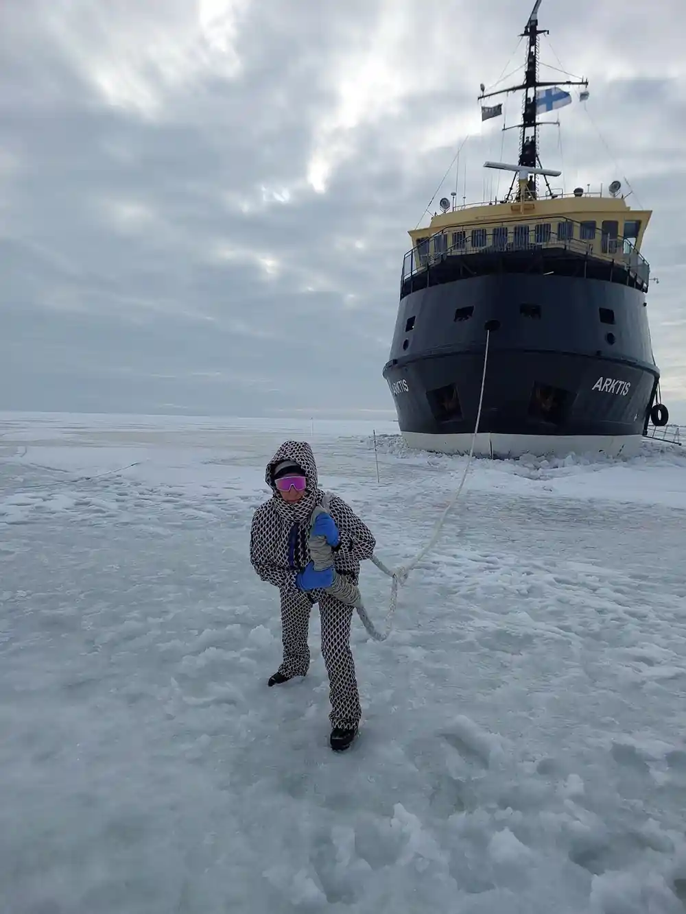 A visitor on the ice in front of Arktis under a cloudy sky