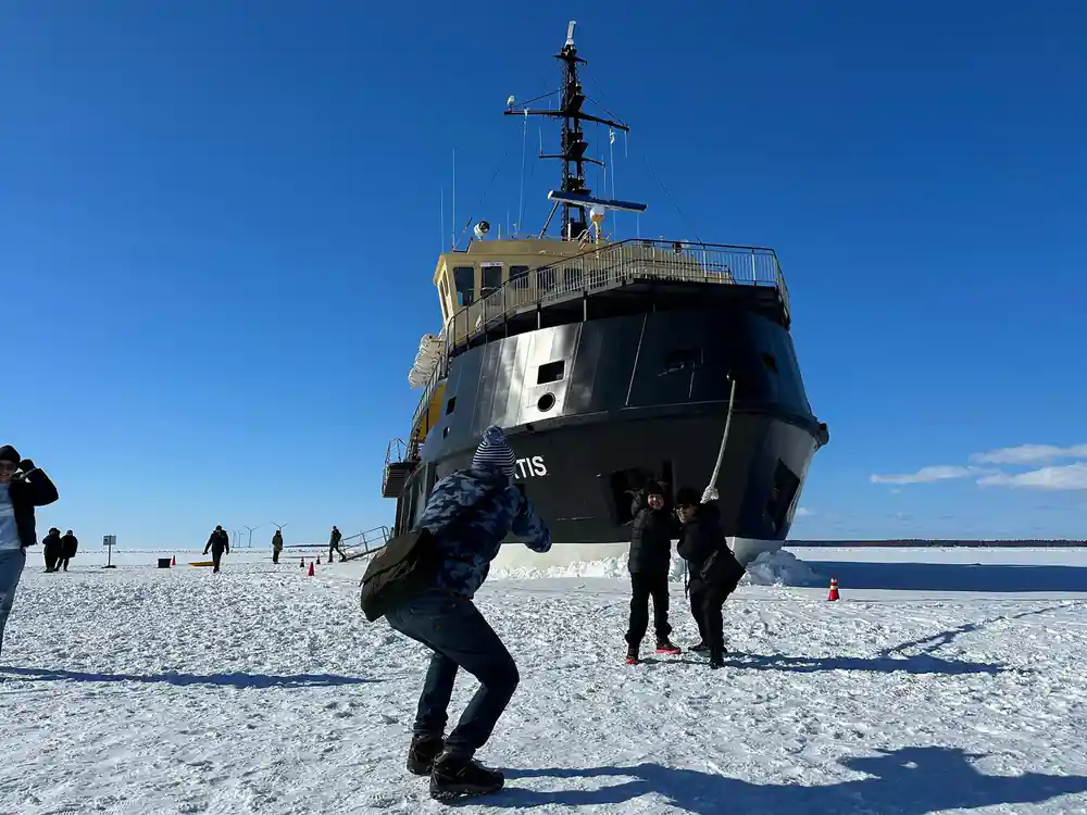 A visitor standing in front of the bow of Arktis on the ice